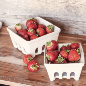 Two containers filled with fresh strawberries on a wooden surface.